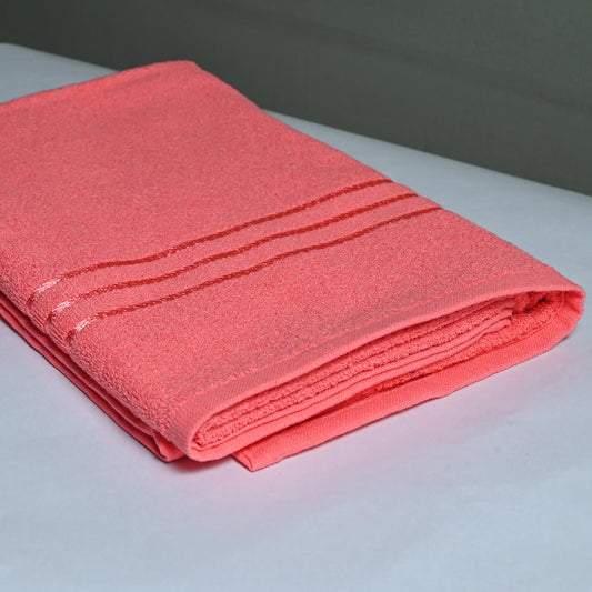 Folded pink towel on a white surface with a blurred background