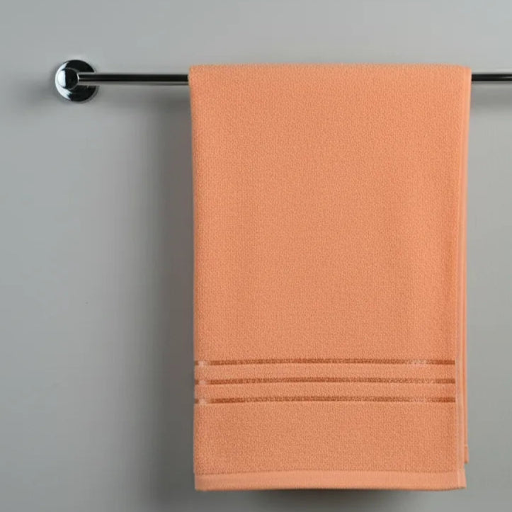 Orange towel hanging on a silver towel rack against a gray background