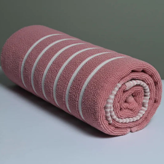 Rolled pink towel with white stripes on a light gray surface and background