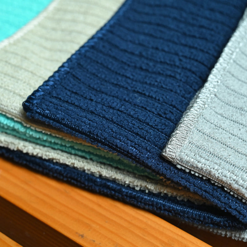 Stack of folded fabric swatches in various colors on a wooden surface