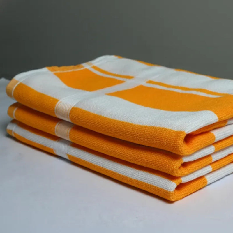 Stack of yellow and white checkered towels on a white surface with a gray background