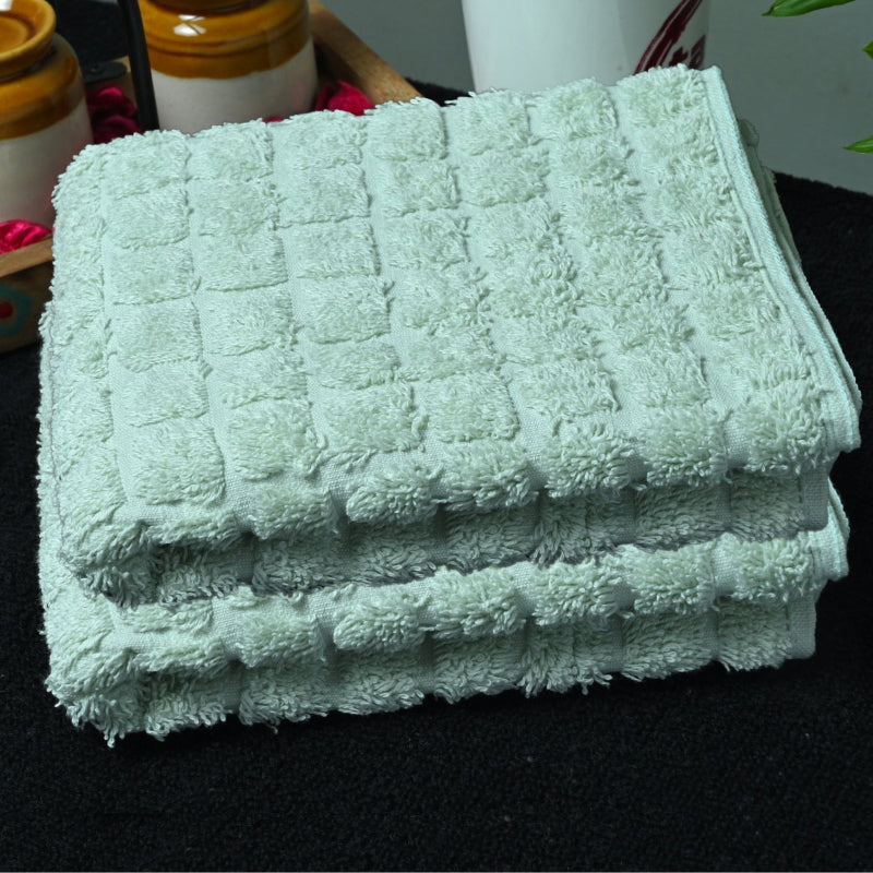 Stack of light green bath towels on a black surface with blurred background