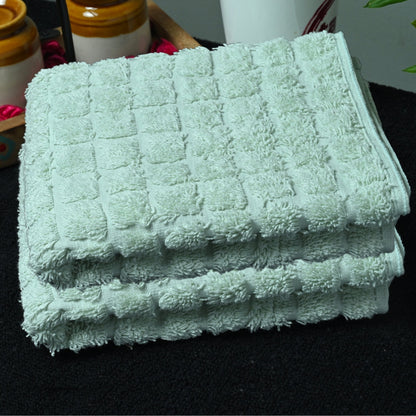 Stack of light green bath towels on a black surface with blurred background