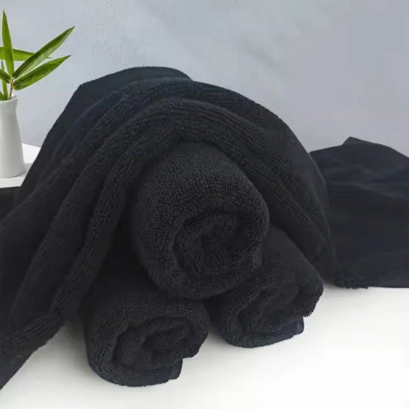 Stack of black towels on a white surface with a gray background