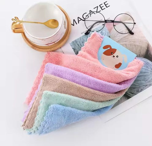 Stack of colorful towels with a cup, saucer, spoon, and glasses in the background.