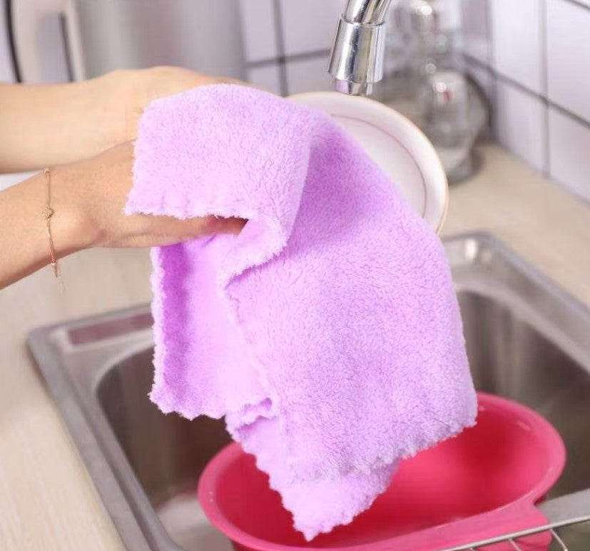 Person holding a purple towel over a pink basin in a kitchen setting