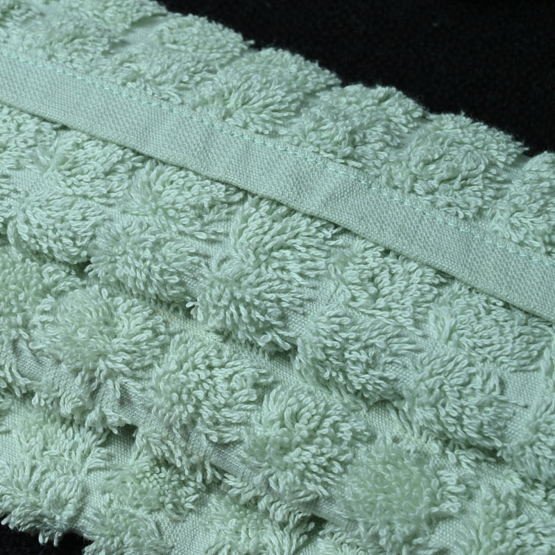 Close-up of a textured green towel with a ribbon on a black background