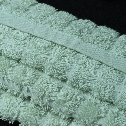 Close-up of a textured green towel with a ribbon on a black background
