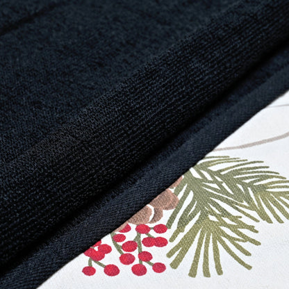 black towels next to a patterned fabric with green leaves and red berries