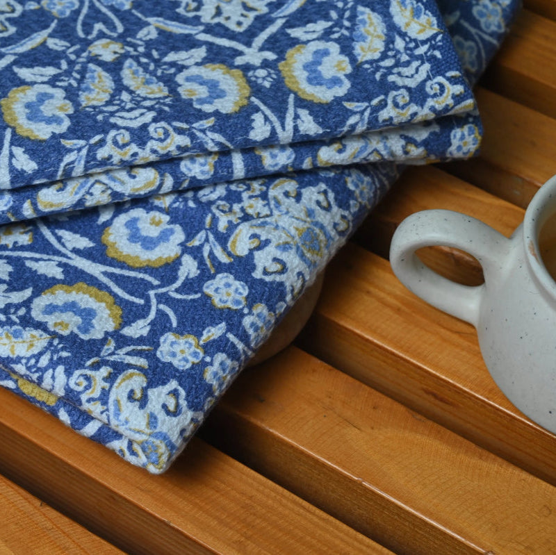 Blue floral hand towe on a wooden surface with a ceramic mug.