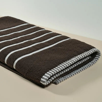 Folded brown towel with white stripes on a beige surface