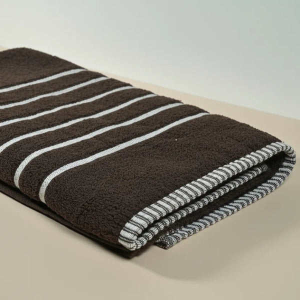 Folded brown towel with white stripes on a beige surface