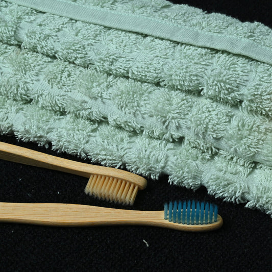 Verdajoy shower gel bottle with a toothbrush and scrubber on a aqua green hand towel