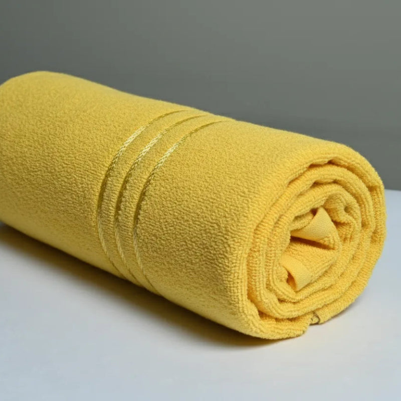 Rolled yellow towel on a white surface with a gray background