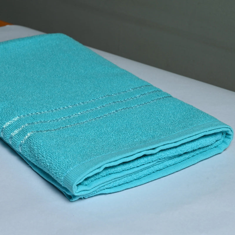 Folded Cyan towel on a white surface with a blurred background