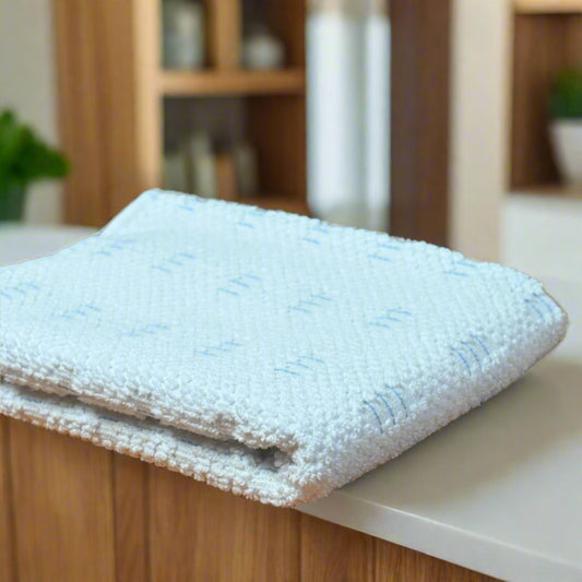 Stack of white towels on a wooden surface with a neutral background