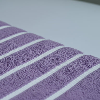 Fabric Closeup of purple bath towel with 4 strips of white color.
