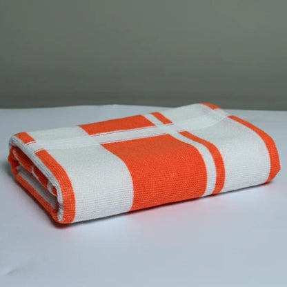 Folded orange and white striped towel on a gray background