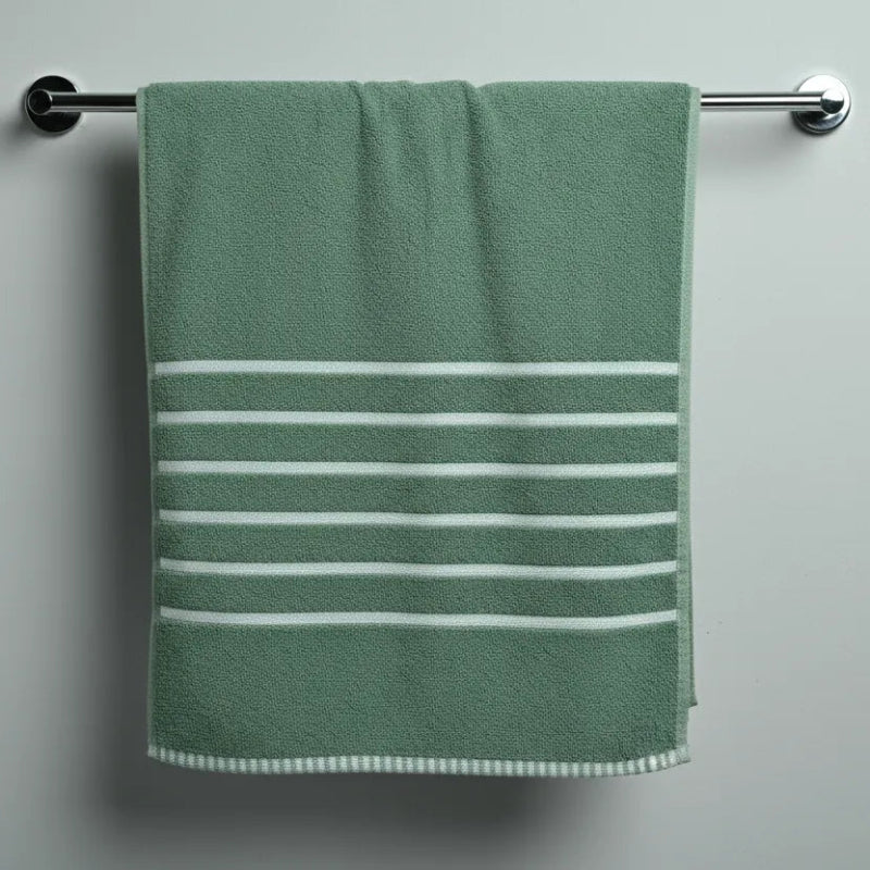 Green towel with white stripes hanging on a silver towel rack against a gray wall.