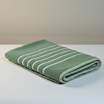 Folded green towel with white stripes on a white surface