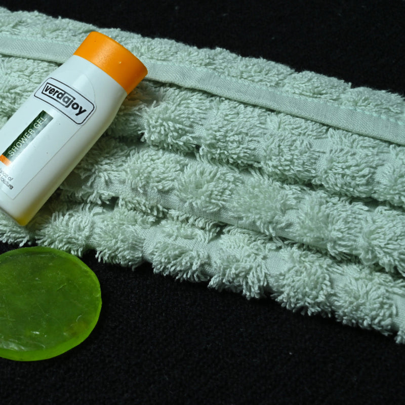 Small bottle with orange cap and green disc on a aqua green towel