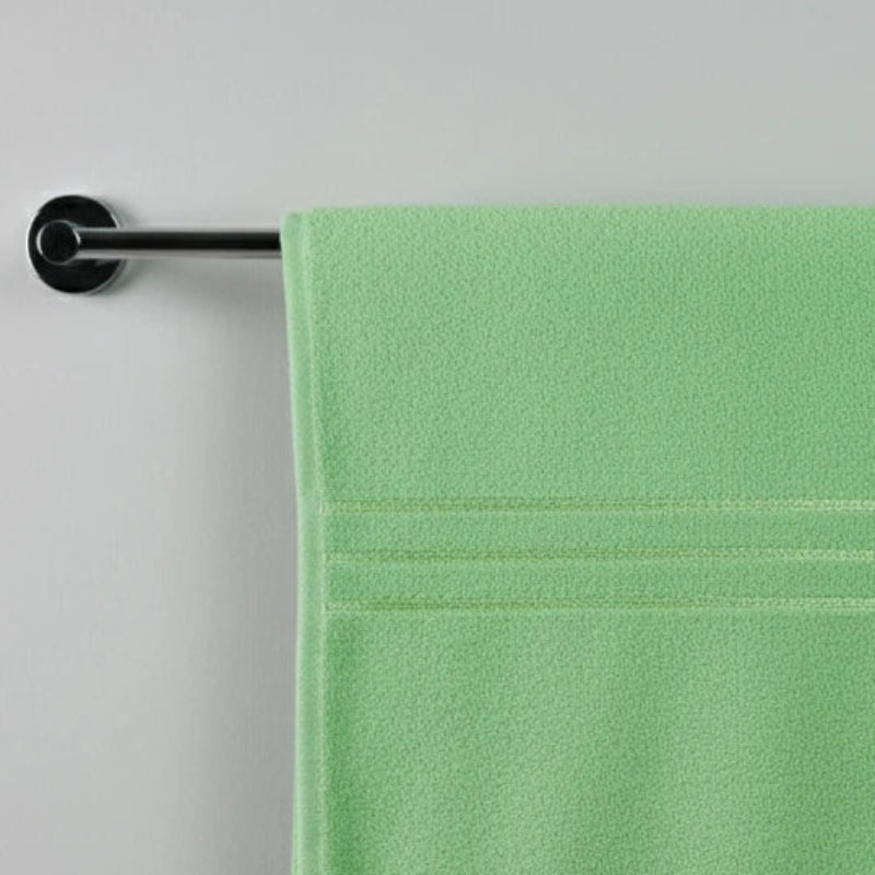 Green towel hanging on a silver towel rack against a gray background