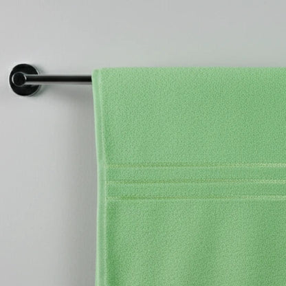 Green towel hanging on a silver towel rack against a gray background