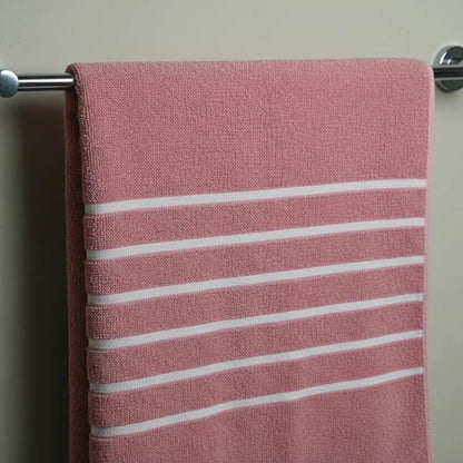 Pink towel with white stripes hanging on a metal towel rack against a plain wall.