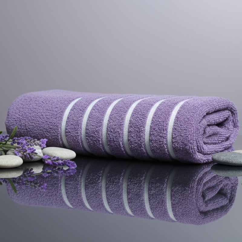 Folded purple towel on a glossy surface with lavender flowers around.