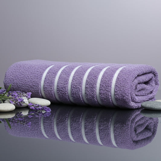 Folded purple towel on a glossy surface with lavender flowers around.