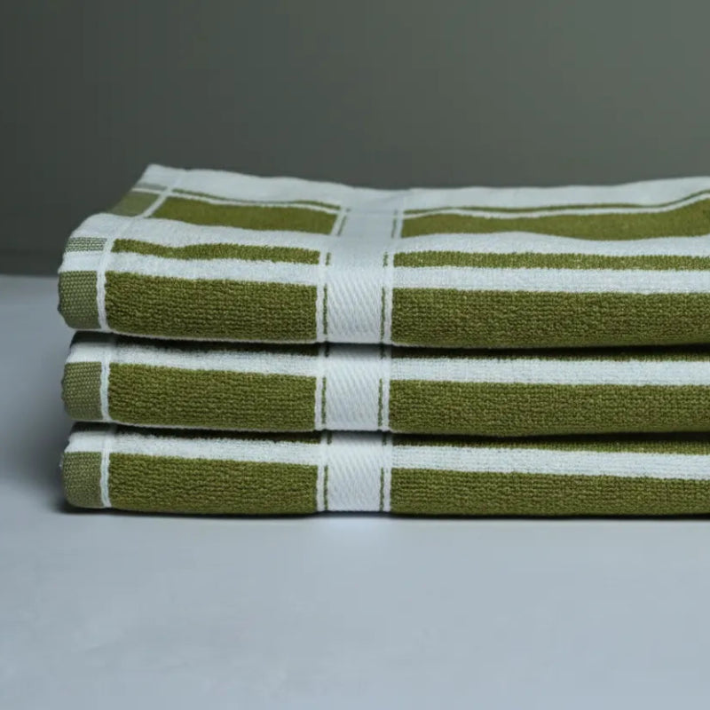 Stack of olive green and white striped towels on a gray background