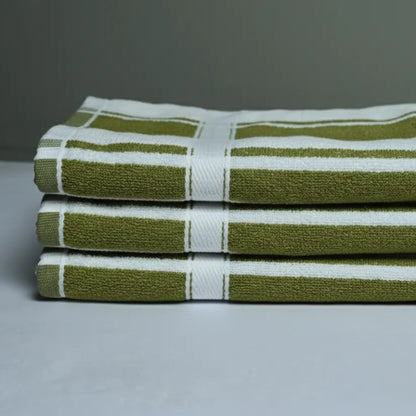 Stack of olive green and white striped towels on a gray background