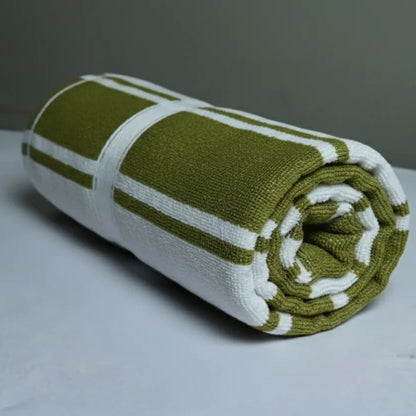 Rolled-up olive green and white towel on a light gray surface