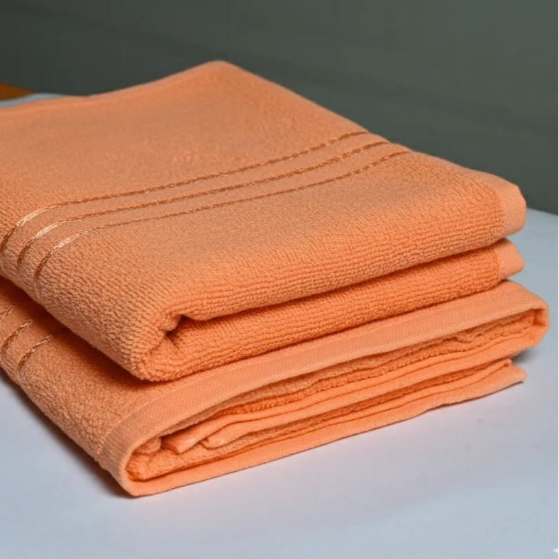 Stack of orange towels on a light gray surface with a neutral background