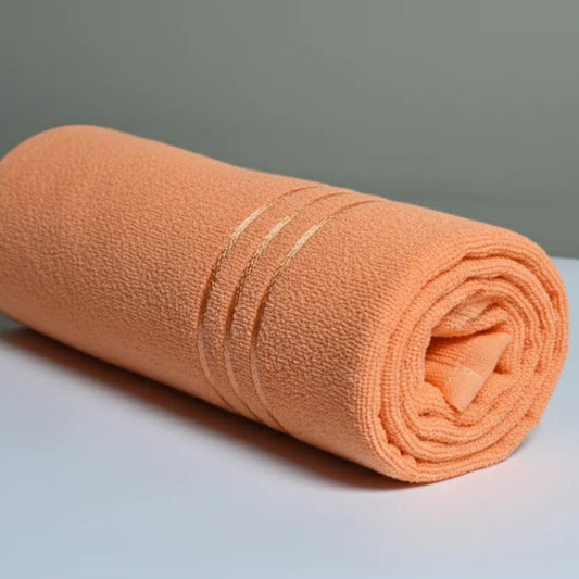 Rolled-up peach-colored towel on a light gray surface with a neutral background