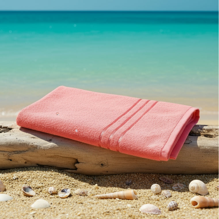 Folded pink towel on a wood at beach with sea at background