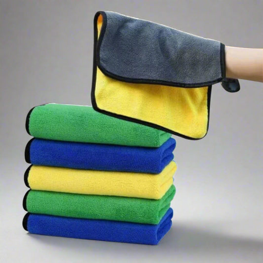 Stack of folded microfiber cloths in green, blue, and yellow with a gray and yellow mitt on a white background.