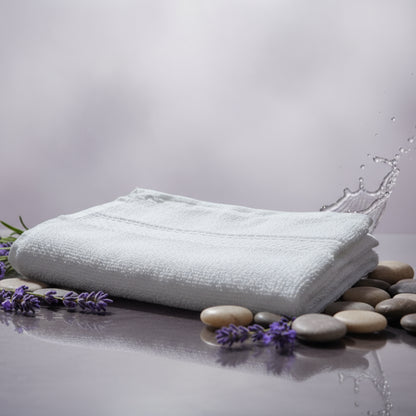 White towel on a purple background with stones and lavender flowers around.