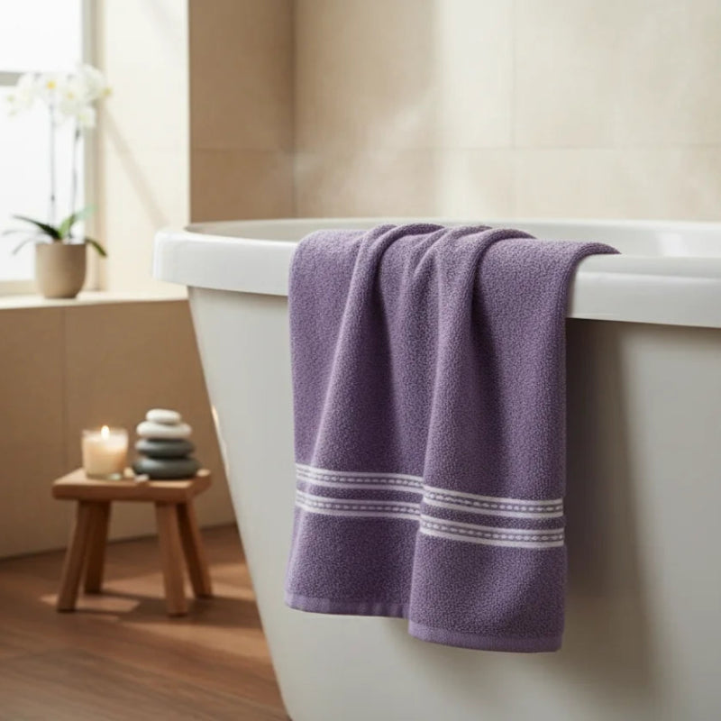 Purple towel draped over a white bathtub in a bathroom setting.