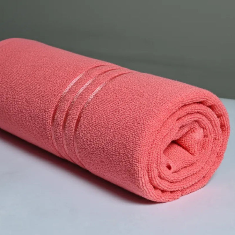 Rolled pink towel on a white surface with a gray background