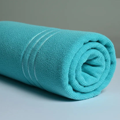 Rolled cyan towel on a gray surface with a neutral background