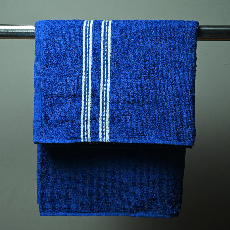 Blue towel with white stripes hanging on a towel rack against a gray wall.