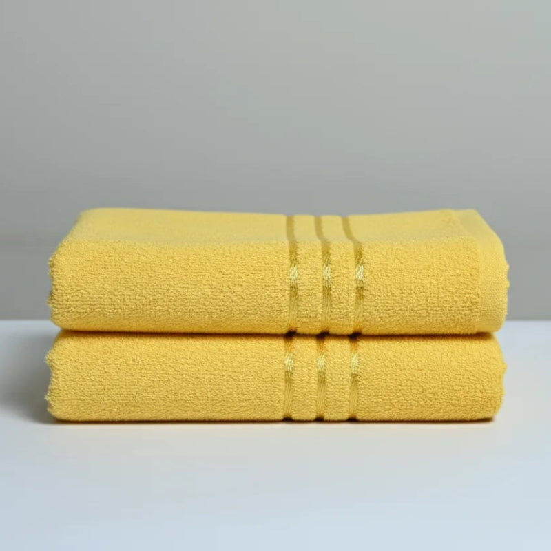 Two yellow towels stacked on a white surface with a gray background