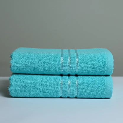 Two cyan towels stacked on a light gray surface with a neutral background