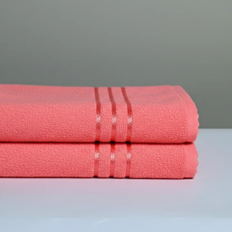 Two folded pink towels on a gray surface with a gray background