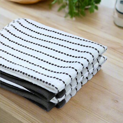 Stack of folded white towels with black patterns on a beige background