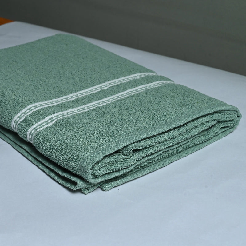 Folded green towel with white stripes on a white surface