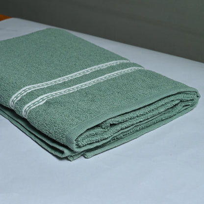 Folded green towel with white stripes on a white surface