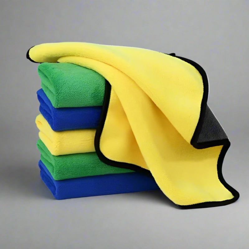 Stack of yellow, green and blue microfiber cloths on a white background