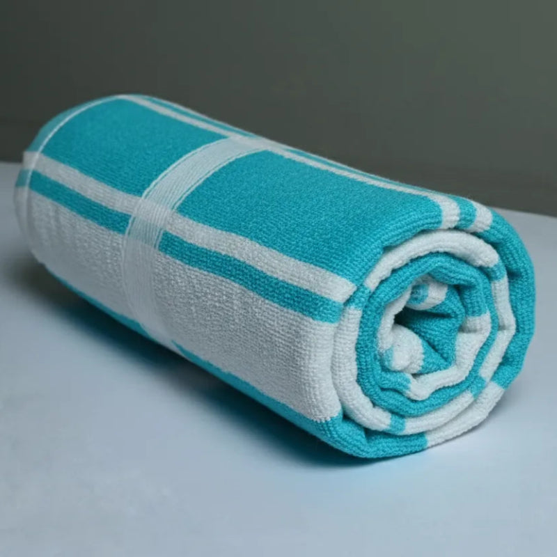 Rolled-up turquoise and white towel on a light gray surface with a neutral background